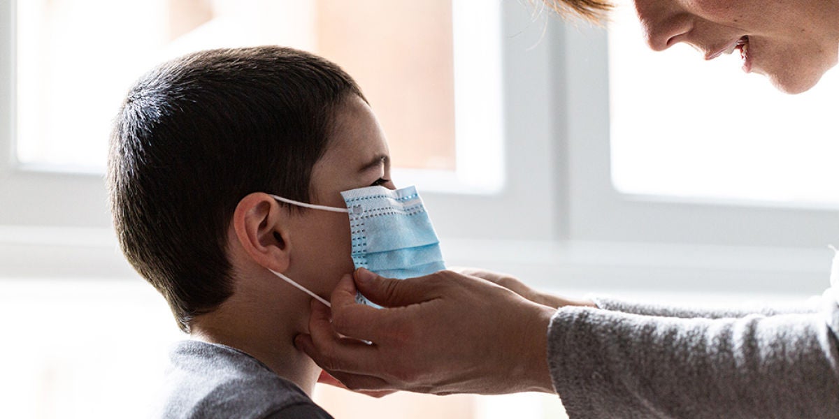 Una mujer coloca una mascarilla a un niño