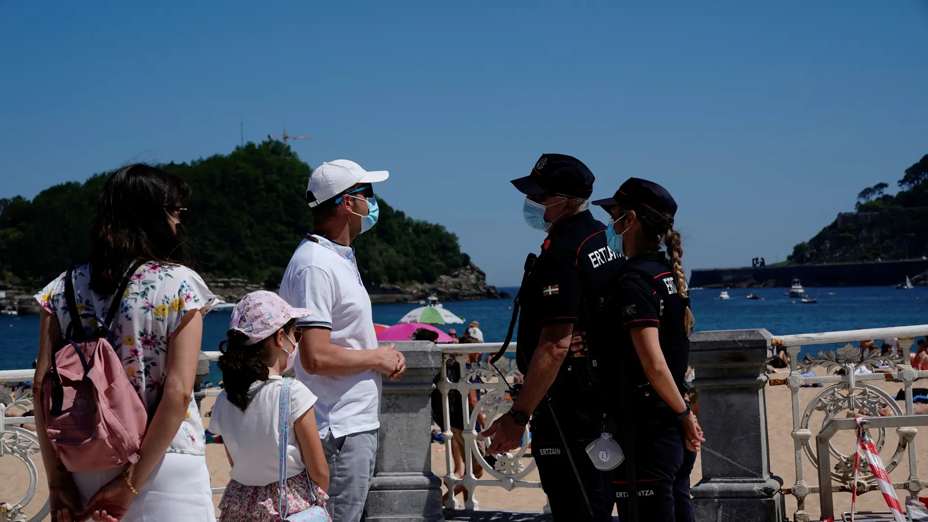 Una familia dialoga con agentes de la Policía en la playa de Ondarreta, en San Sebastián