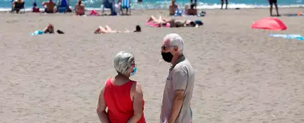 Personas con mascarilla en una playa Personas con mascarilla en una playa