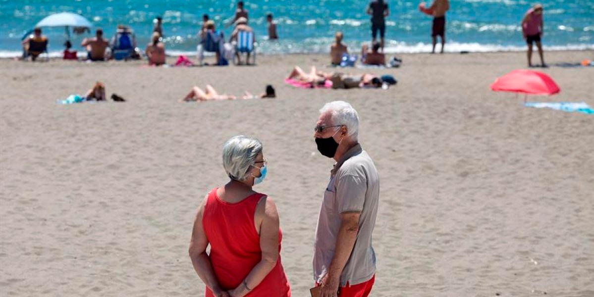 Personas con mascarilla en una playa
