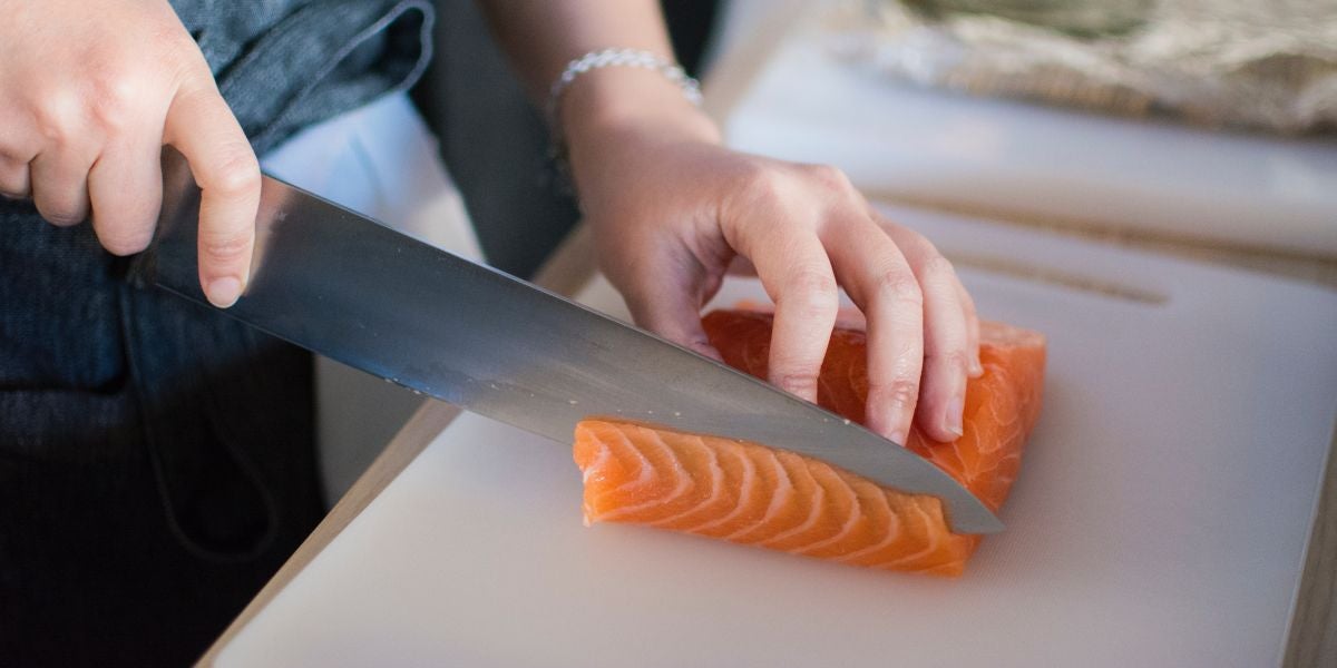 Una persona cortando salmón