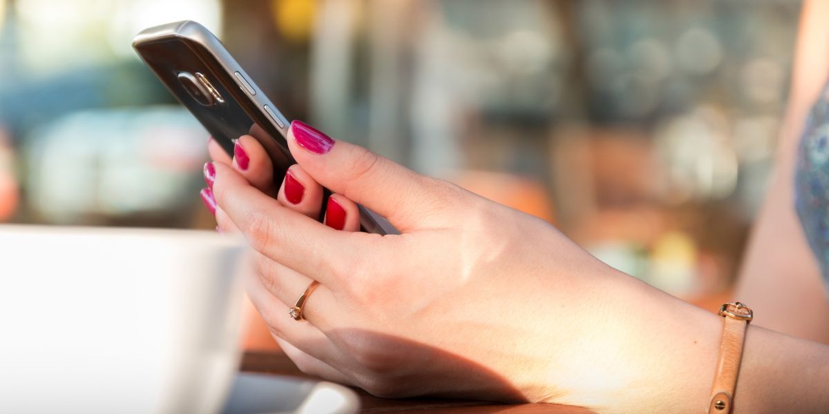 Imagen de una mujer usando un teléfono móvil en un bar
