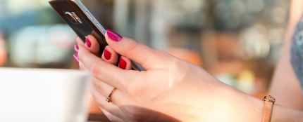 Imagen de una mujer usando un tel&eacute;fono m&oacute;vil en un bar