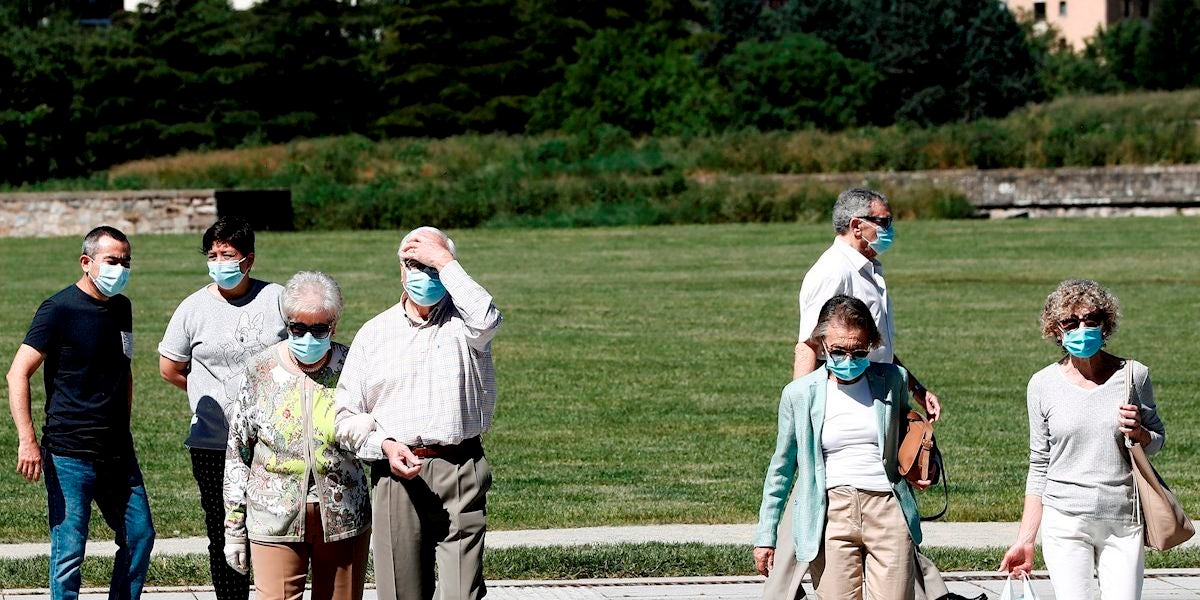 Un grupo de personas con mascarilla pasean por un parque
