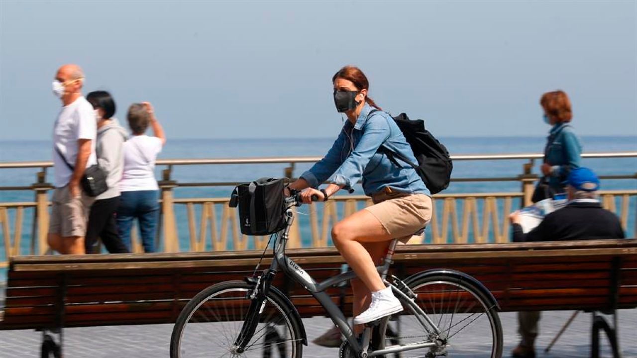Una mujer pasea en bicicleta protegida con una mascarilla por el paseo de la Zurriola de San Sebastián Una mujer pasea en bicicleta protegida con una mascarilla por el paseo de la Zurriola de San Sebastián