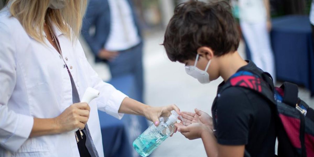 Un niño con mascarilla se lava las manos con gel en un colegio de Barcelona