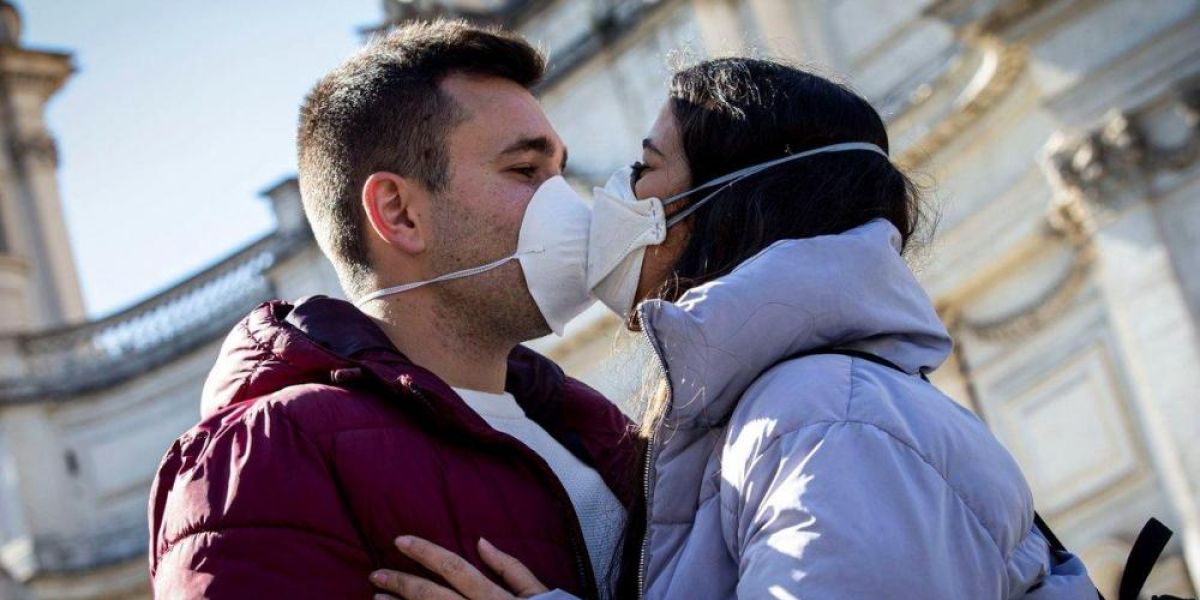 Dos jóvenes besándose con mascarilla