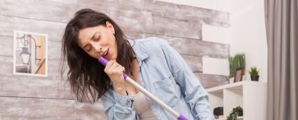 Imagen de archivo de una mujer cantando con una fregona Imagen de archivo de una mujer cantando con una fregona